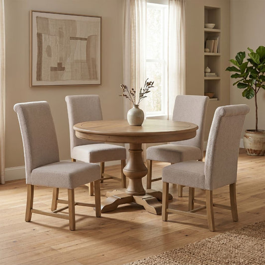 Round wooden dining table with four matching chairs in a well-lit room.