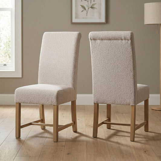 Two beige upholstered chairs with pine wood legs.