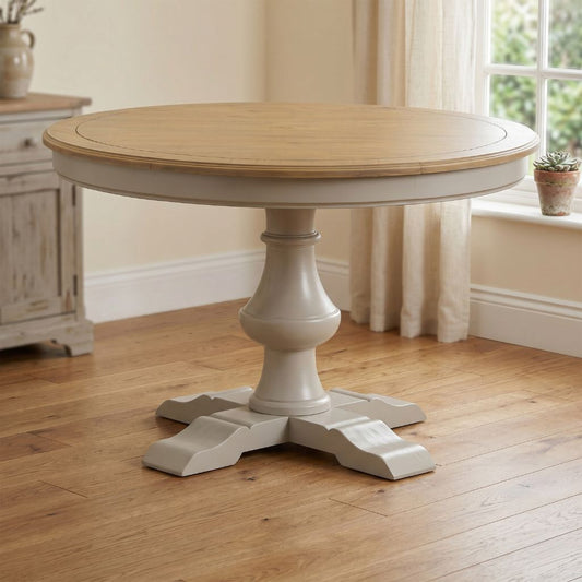 A round pedestal dining table with a pine wood top and a rustic grey base