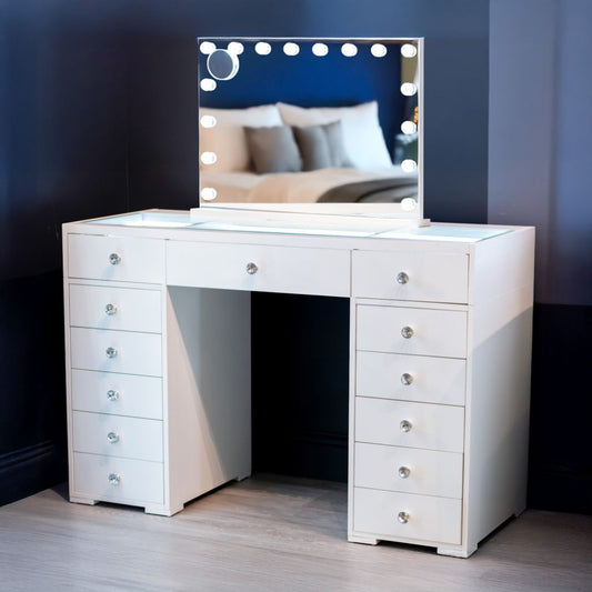 White wooden vanity table with multiple drawers and a Hollywood mirror