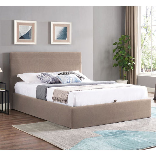 Beige upholstered bed in a room with gray walls, framed pictures, and a plant.