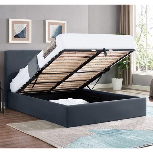 Blue upholstered bed with wooden slats in a room with gray walls and a window.