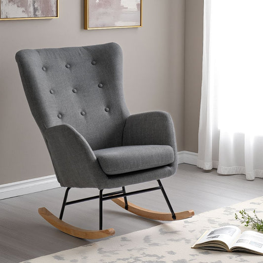 Gray upholstered rocking chair in a room with a book and plant on a table.