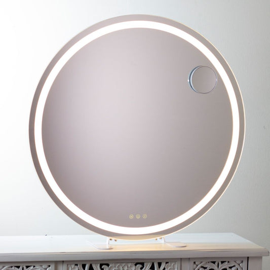 Round illuminated mirror on a white surface with a light gray background