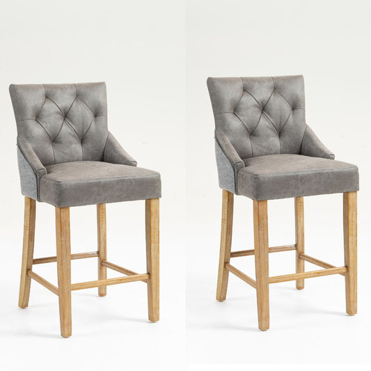 Two matching bar stools with grey tufted faux leather upholstery and natural wood legs.