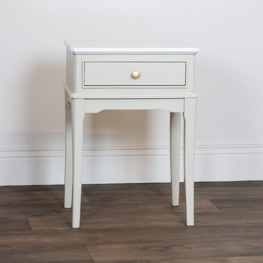Stone side table with a drawer against a plain wall.