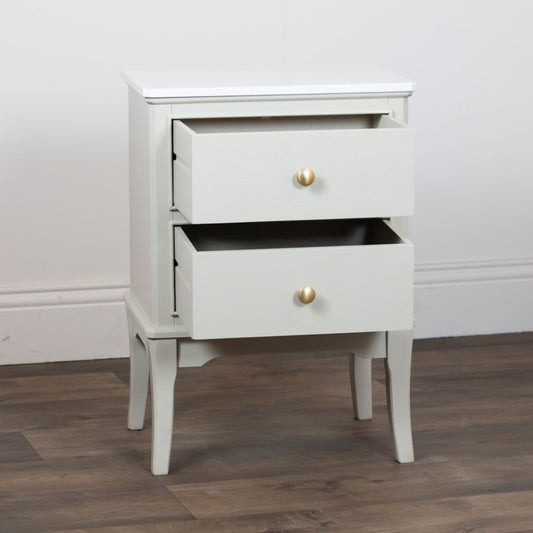 Stone accent table with two drawers and gold knobs on a wooden floor.