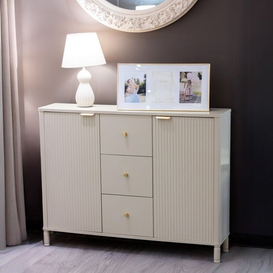 Beige sideboard with a lamp and framed photos against a dark wall.