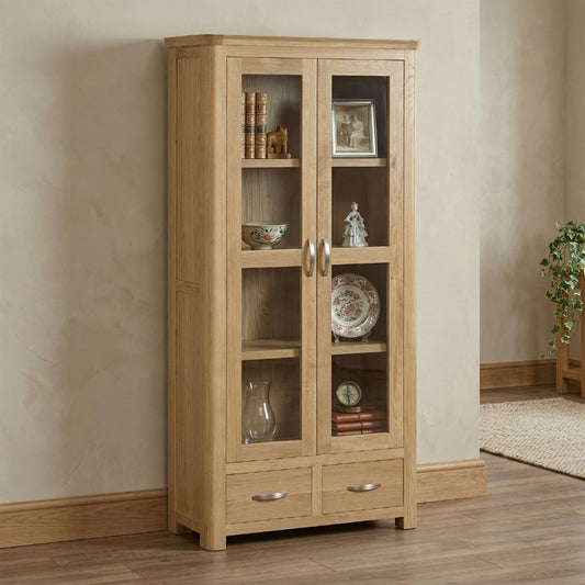 A tall light oak wood display cabinet with two glass doors and two drawers.