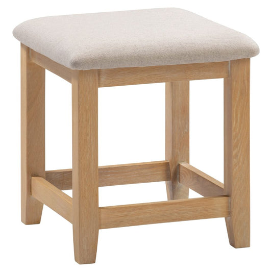 Wooden stool with a beige cushioned seat on a white background