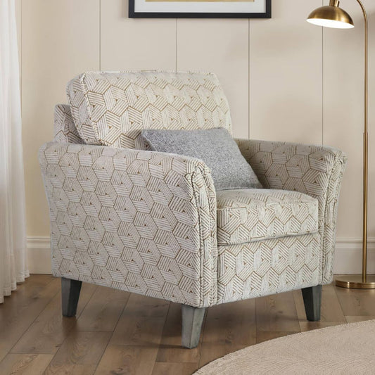 Patterned armchair with a gray pillow in a room with a lamp and framed picture on the wall.