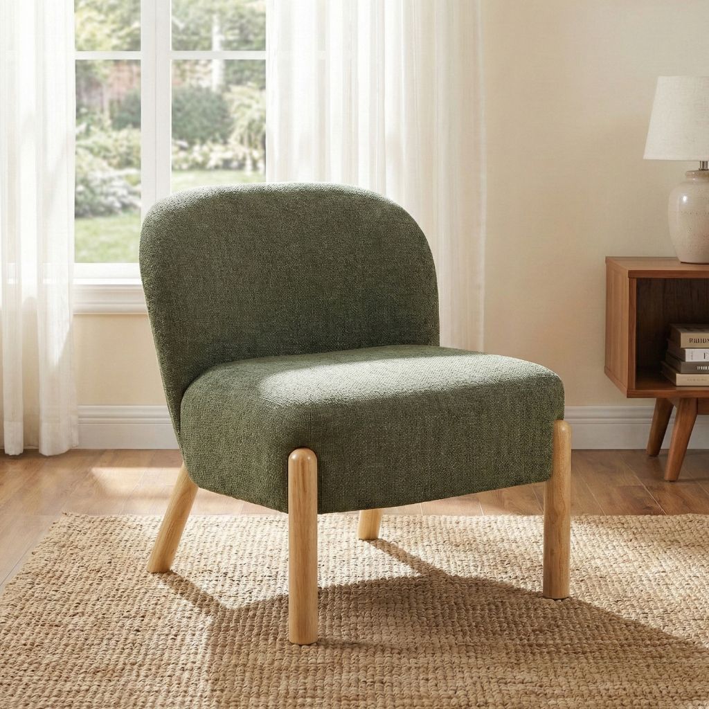 Green upholstered chair with wooden legs in a room with a window and lamp.