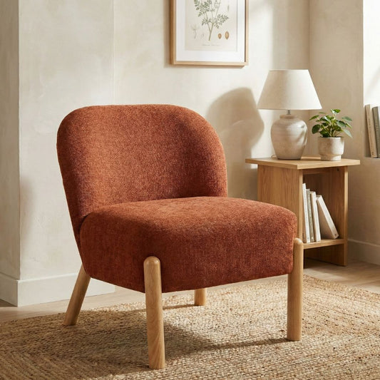 Rust upholstered chair in a room with a lamp and books on a side table.