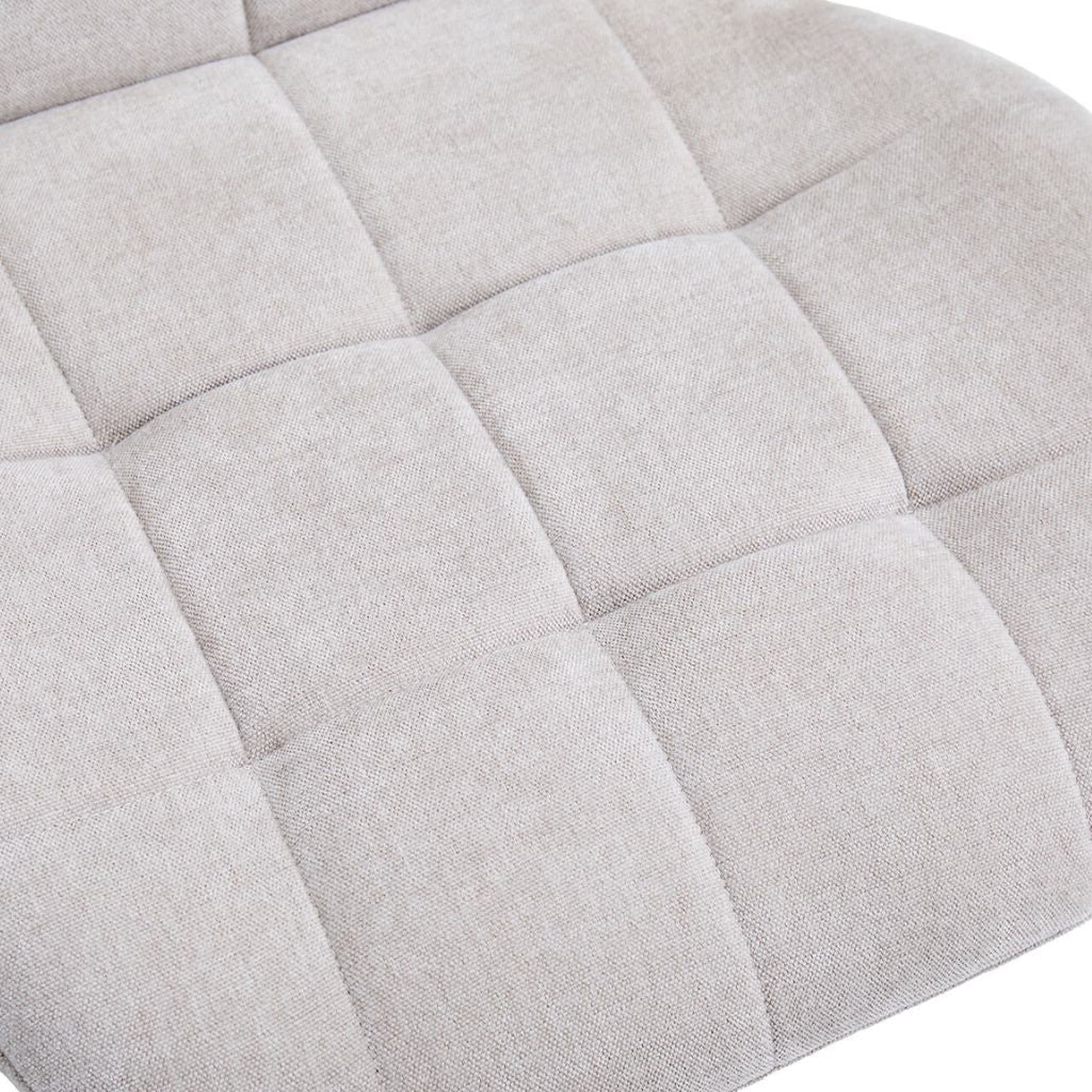 Close-up of the beige fabric seat with a quilted grid pattern.