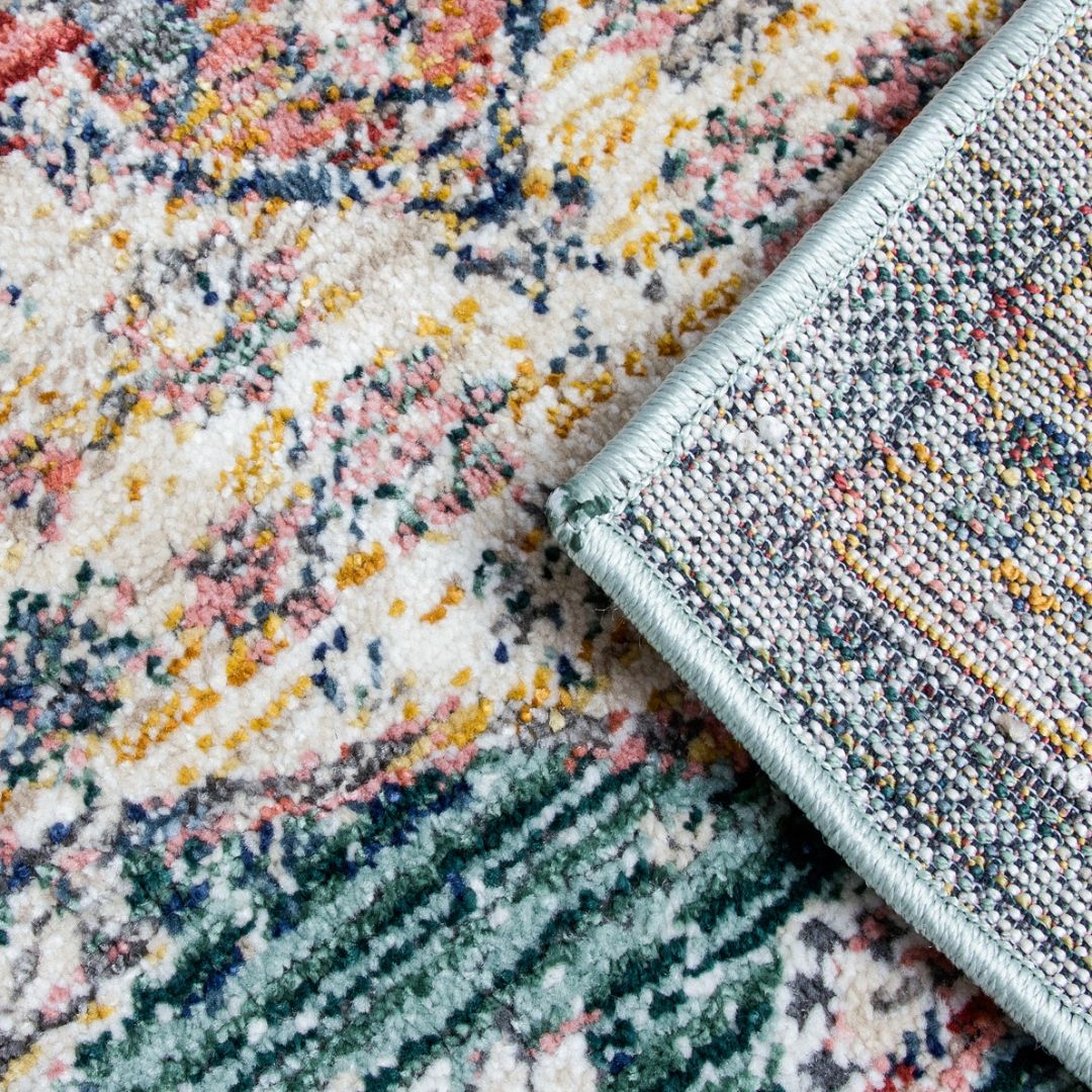 Close-up of a textured rug with multicolor pattern and a corner of a green rug.