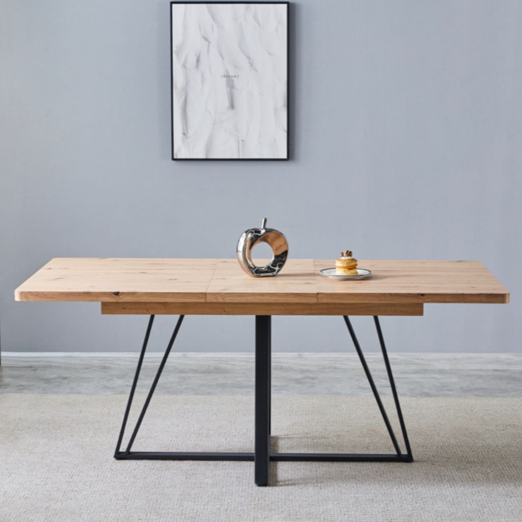 Wooden dining table with black metal legs in a room with a grey wall and abstract art.