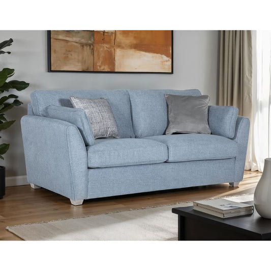 A blue upholstered sofa bed with bolster cushions and accent cushions.