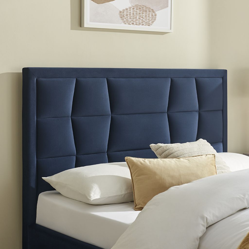 Blue upholstered headboard with pillows on a bed in a bedroom setting.
