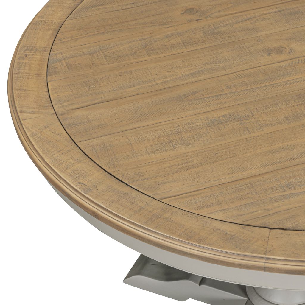 Close-up of a round wooden dining table showing the tabletop with visible pine wood grain and a light grey pedestal base.