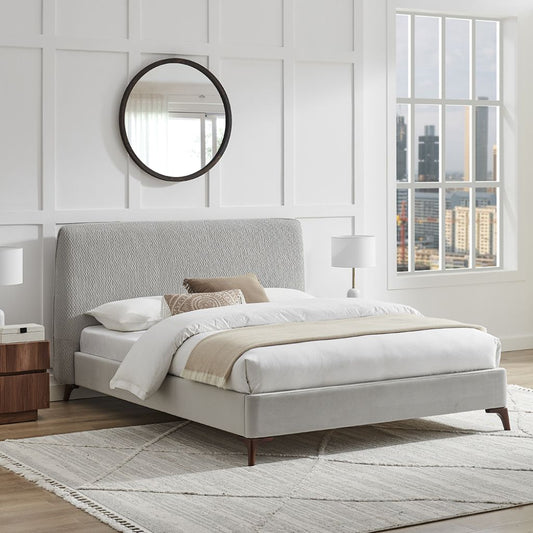 Modern bedroom with a gray upholstered bed, wooden nightstands, and a round mirror.