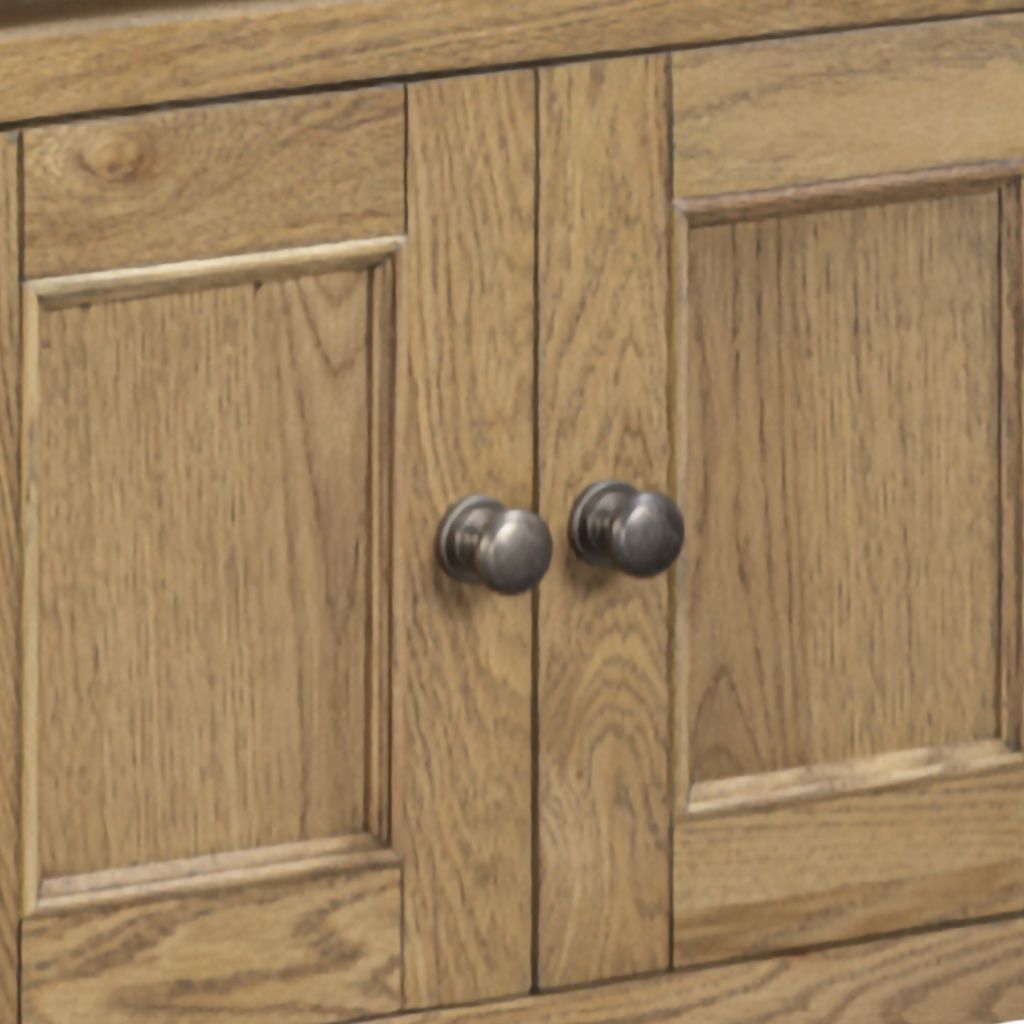 Close-up of a wooden cabinet door with two round dark metal knobs, showing natural oak wood grain