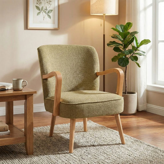 Green armchair in a room with a side table, lamp, and plant.