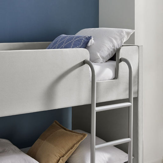 Bunk bed with white mattress and pillows against a blue wall