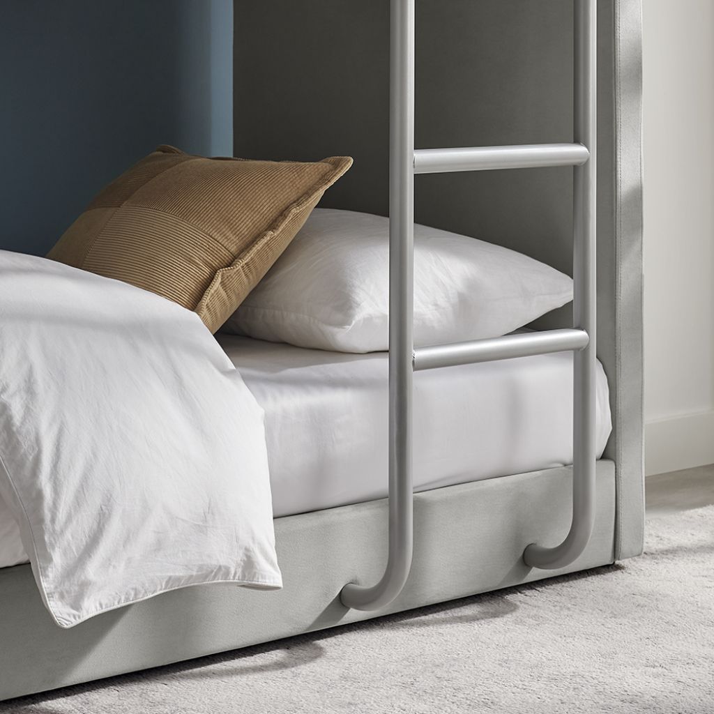Bunk bed with white bedding and a brown pillow against a neutral wall.