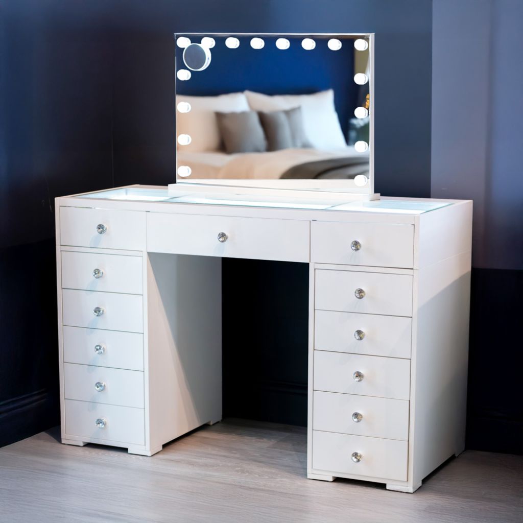 White wooden vanity table with multiple drawers and a Hollywood mirror