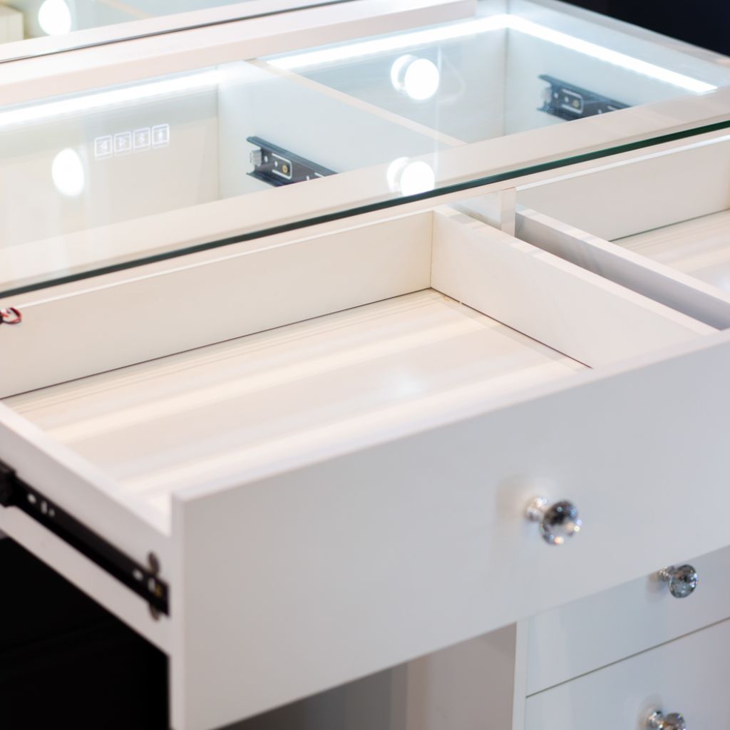 Close-up of a white vanity with open drawer and mirror above.