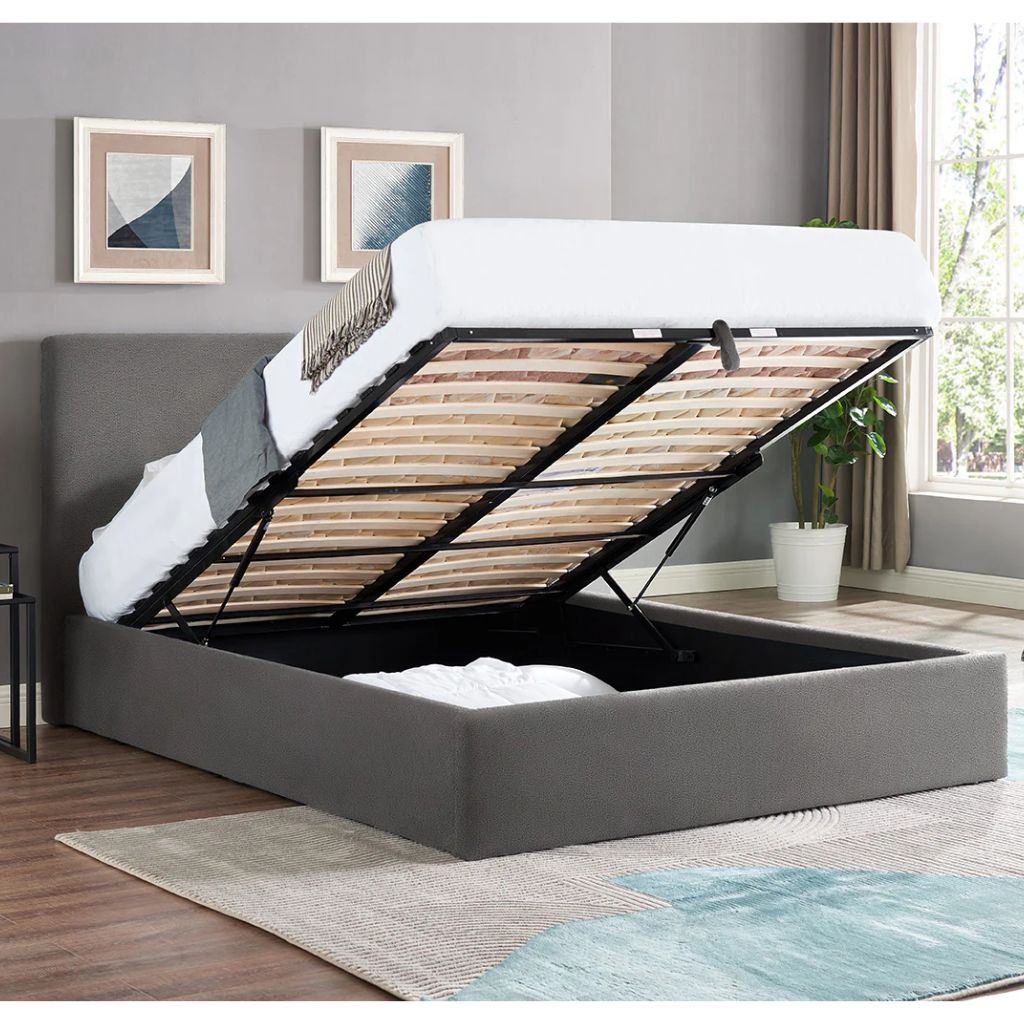 Grey upholstered bed with open storage compartment in a room with gray walls and a window.