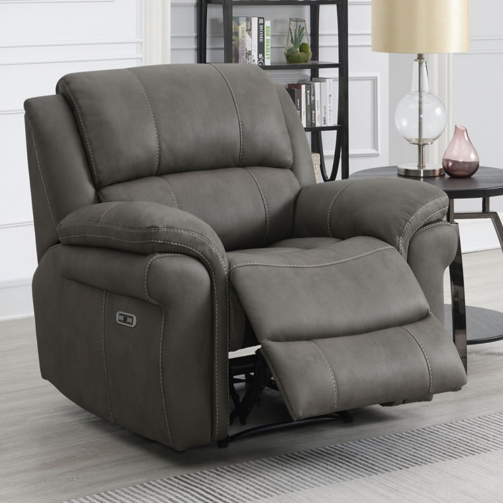Gray recliner chair in a living room setting with a lamp and bookshelf in the background.
