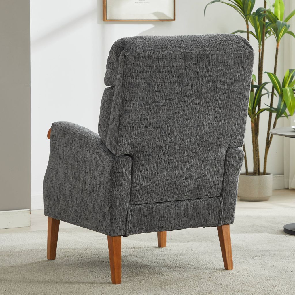 Gray upholstered armchair with wooden legs in a room with a plant and framed picture.