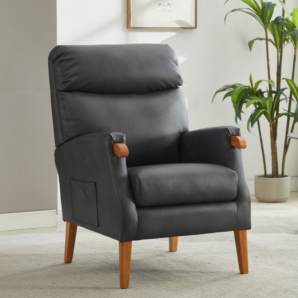 Gray fireside chair with wooden legs in a room with a plant and framed picture on the wall.