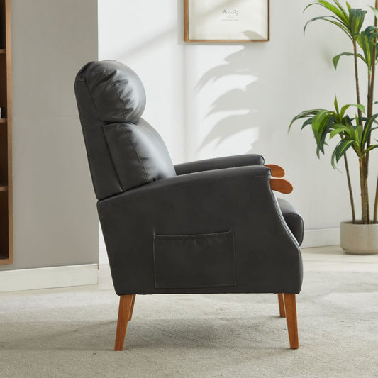 Gray fireside chair with wooden legs in a room with a plant and framed picture on the wall.