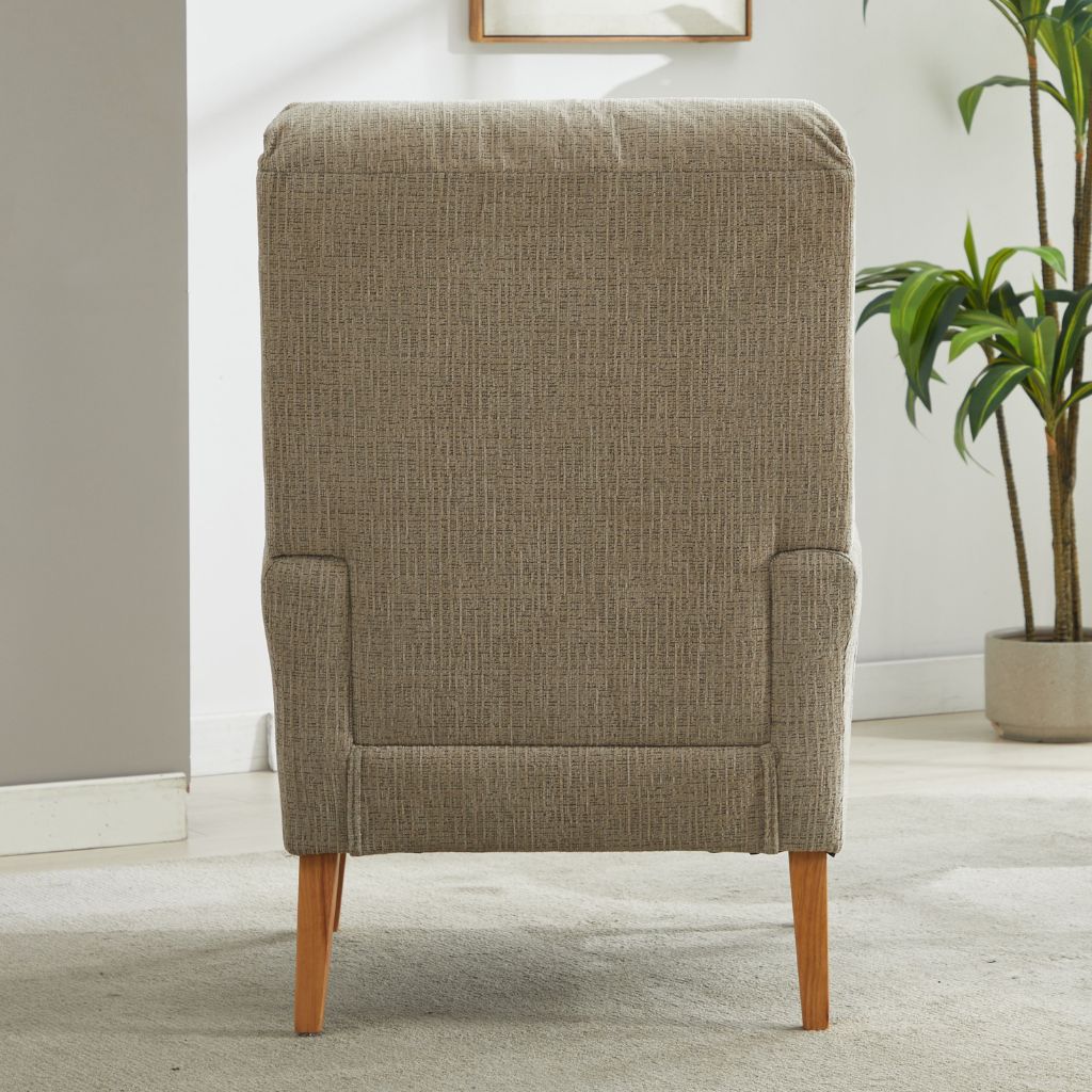 beige upholstered chair with wooden legs in a room with a plant and framed picture on the wall.