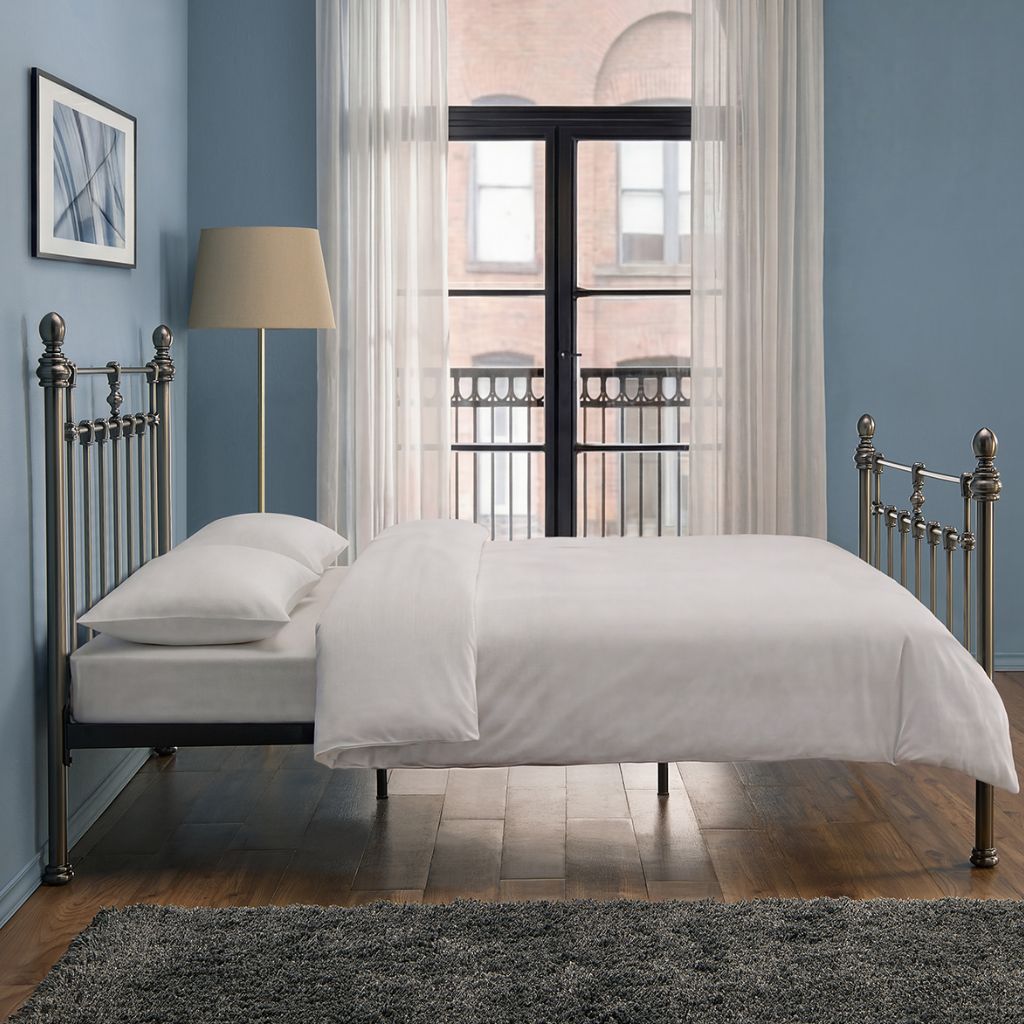 Bedroom with a metal bed frame, white bedding, and a lamp.