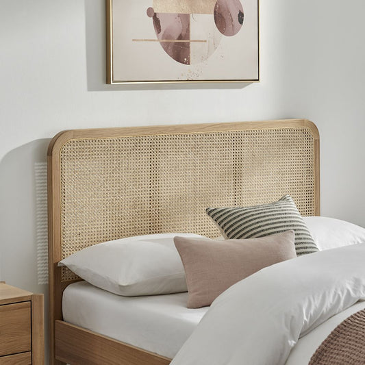 Bedroom with a wicker headboard and decorative pillows on a bed.