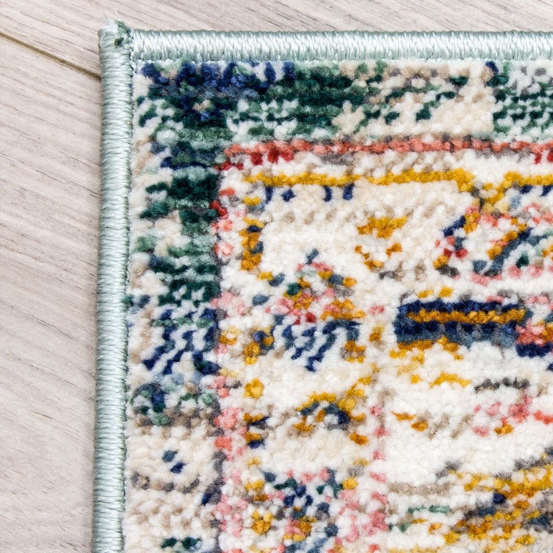Close-up of a multicolored patterned rug corner on a wooden floor.