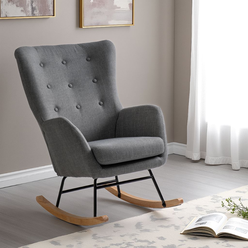 Gray upholstered rocking chair in a room with a book and plant on a table.