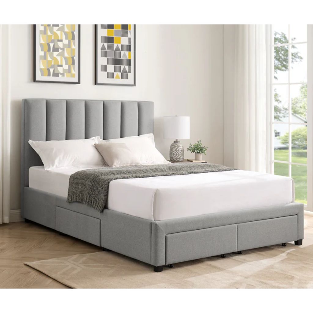 Grey upholstered bed with white bedding in a room with framed artwork on the wall.