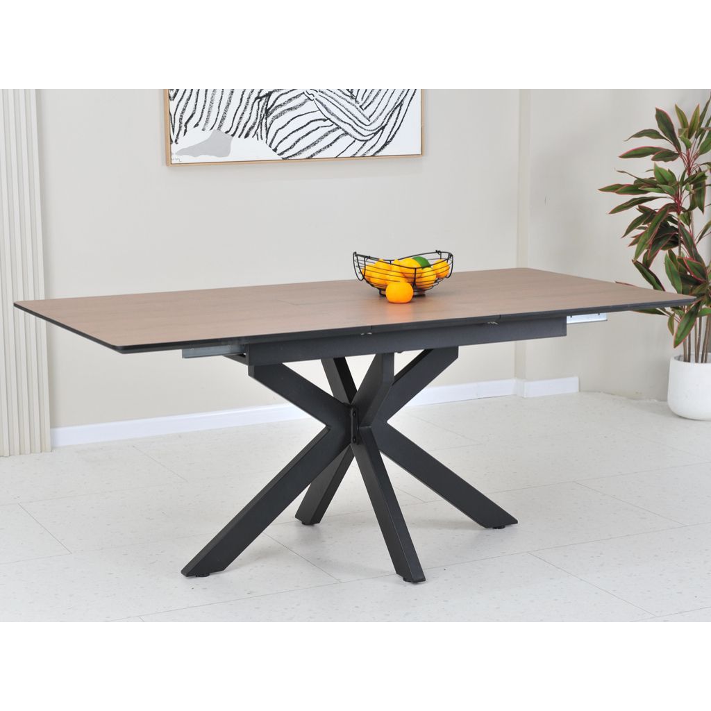 Dining table with wooden top and black metal legs in a room with a plant and abstract art on the wall.