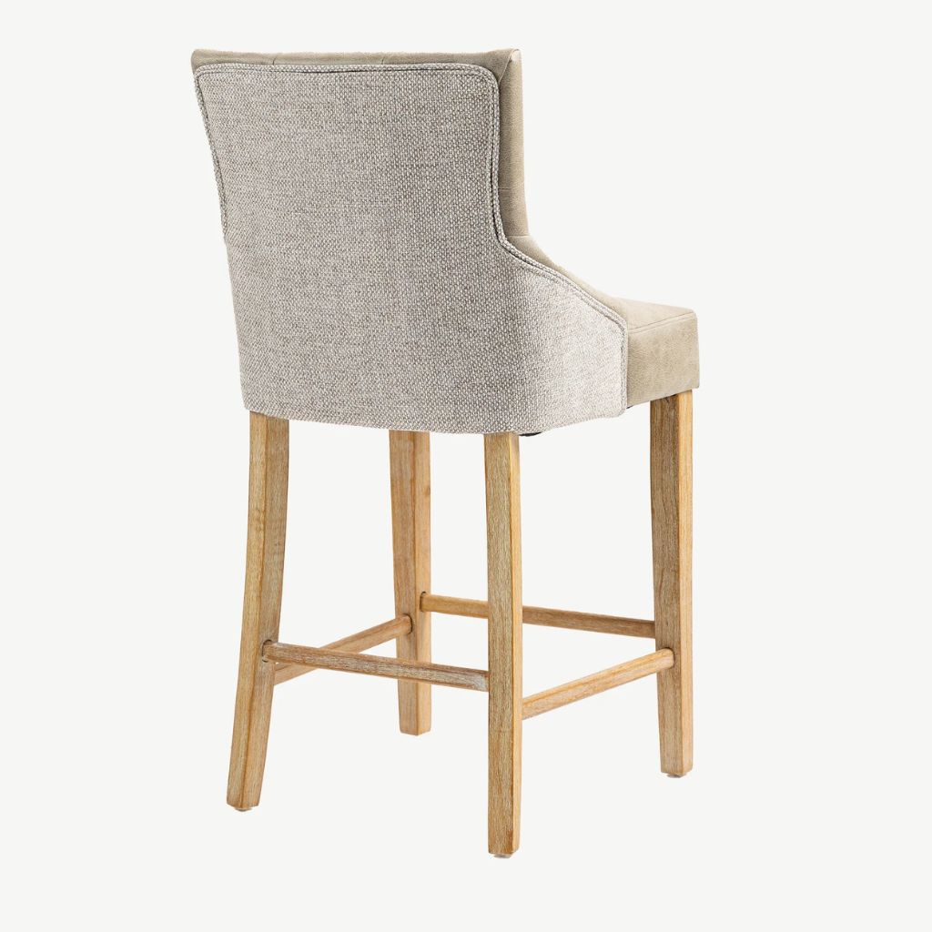 A high-back upholstered bar stool with a textured light beige fabric backrest, supported by four natural wood legs and a wooden footrest.
