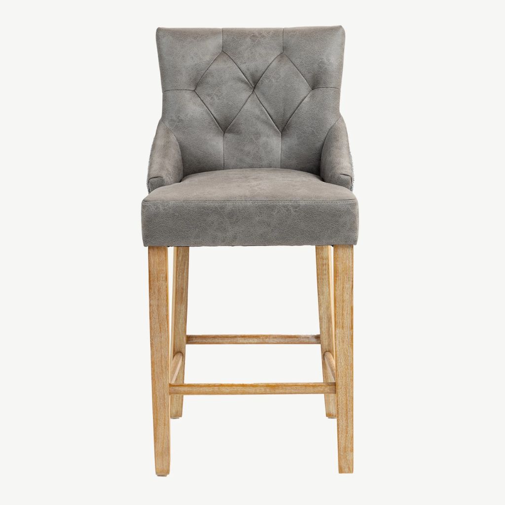 A grey PU upholstered bar stool with a diamond-tufted backrest, armrests, and natural wood legs and footrest.