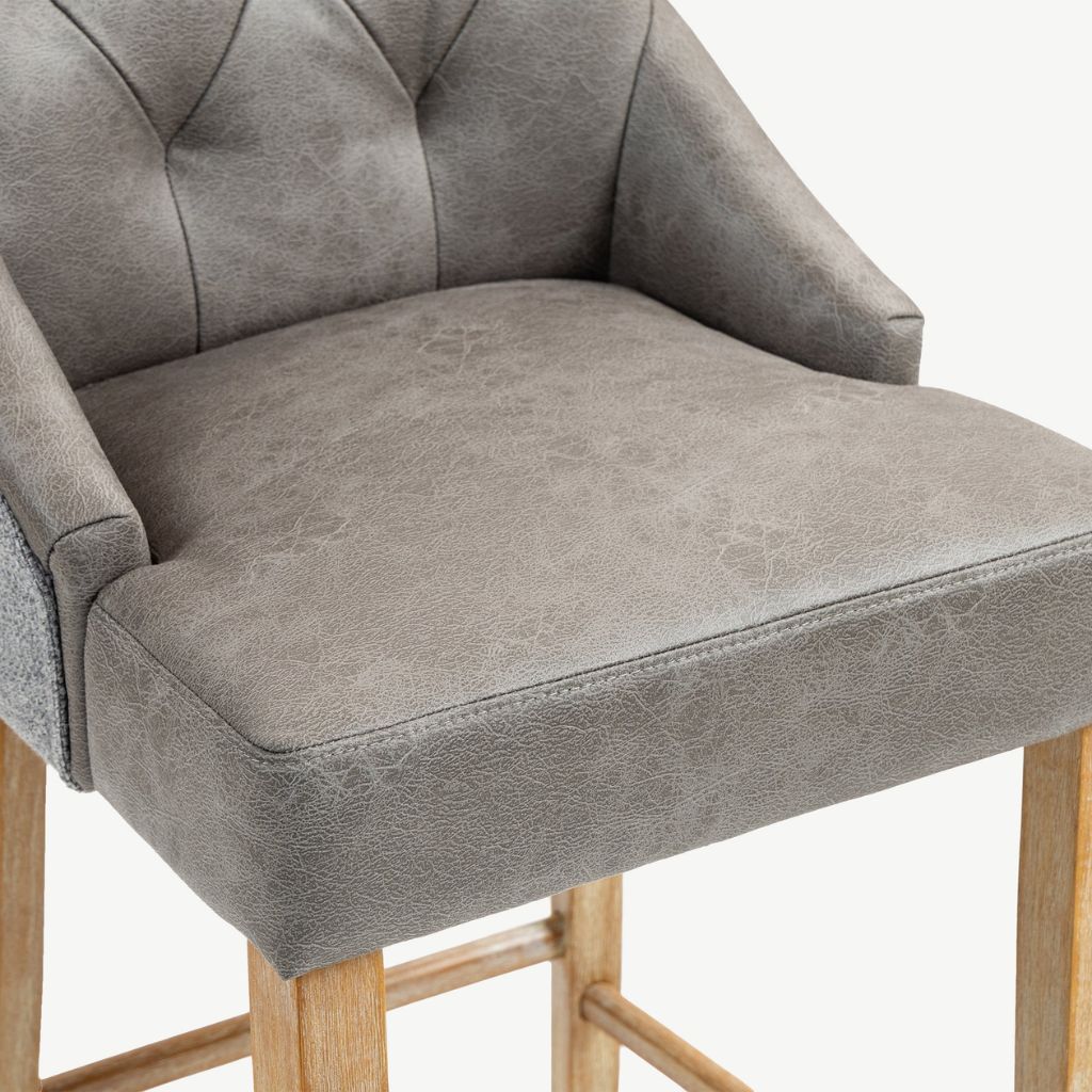 Close up of grey faux-leather barstool.