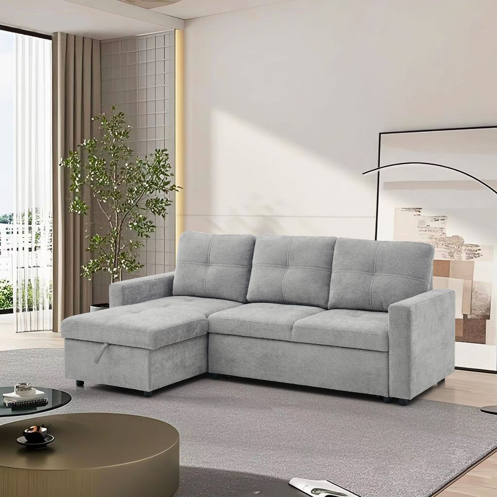 Grey sectional sofa bed in a modern living room with a plant and coffee table.