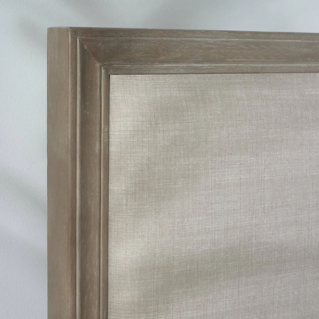 Close-up detail of a bedframe showing a limed oak wooden frame and a ivory upholstery.