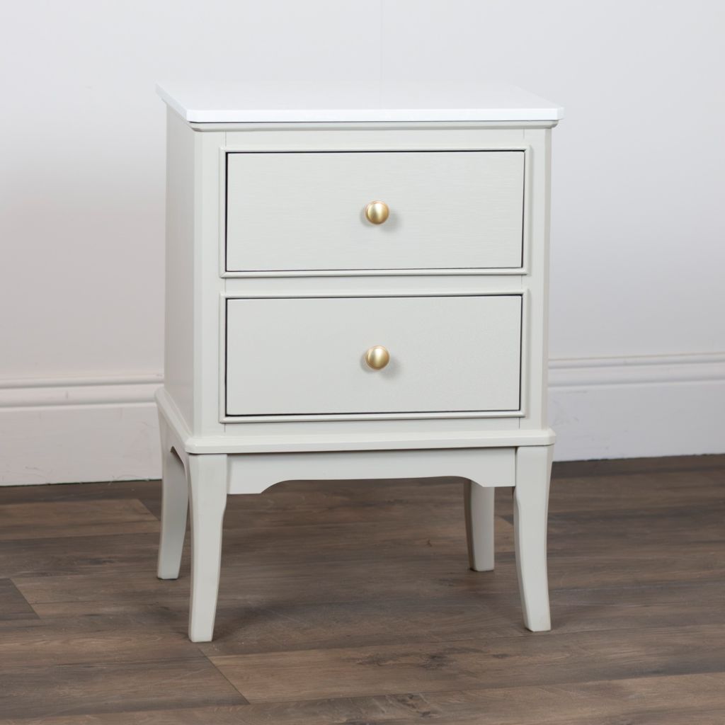 Stone nightstand with two drawers and gold handles on a wooden floor.