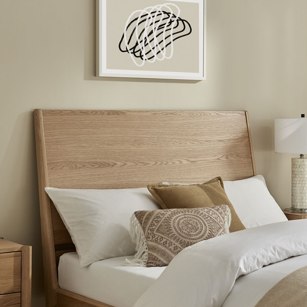 Bedroom with wooden headboard, white bedding, and decorative pillows.