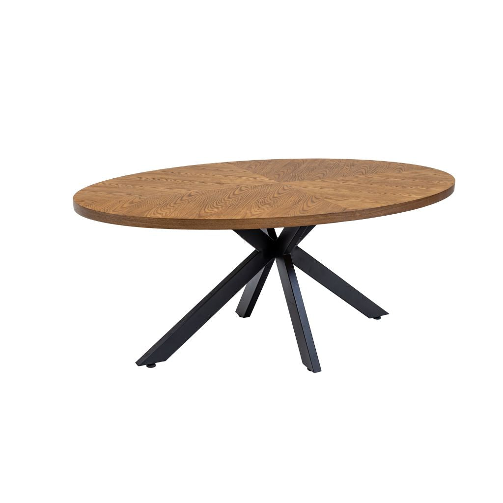 An oval dining table with a medium brown wood veneer top and a black metal X-shaped base.